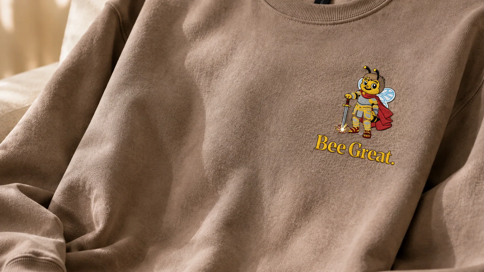 A Brown Savana Bee Cheever sweatshirt with the Bee Great character embroidered on the chest.